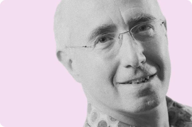 Close-up of a smiling man with glasses against a light purple background.