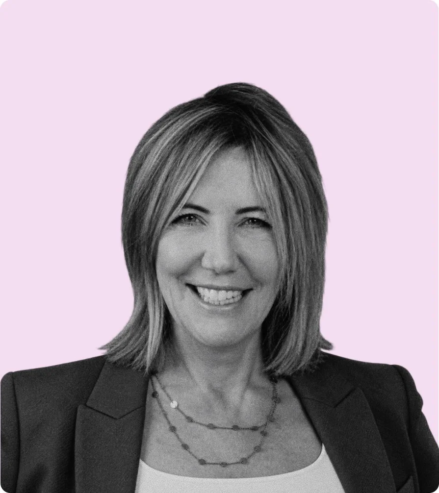 Black and white portrait of a woman with shoulder-length hair, smiling, against a light-colored background.