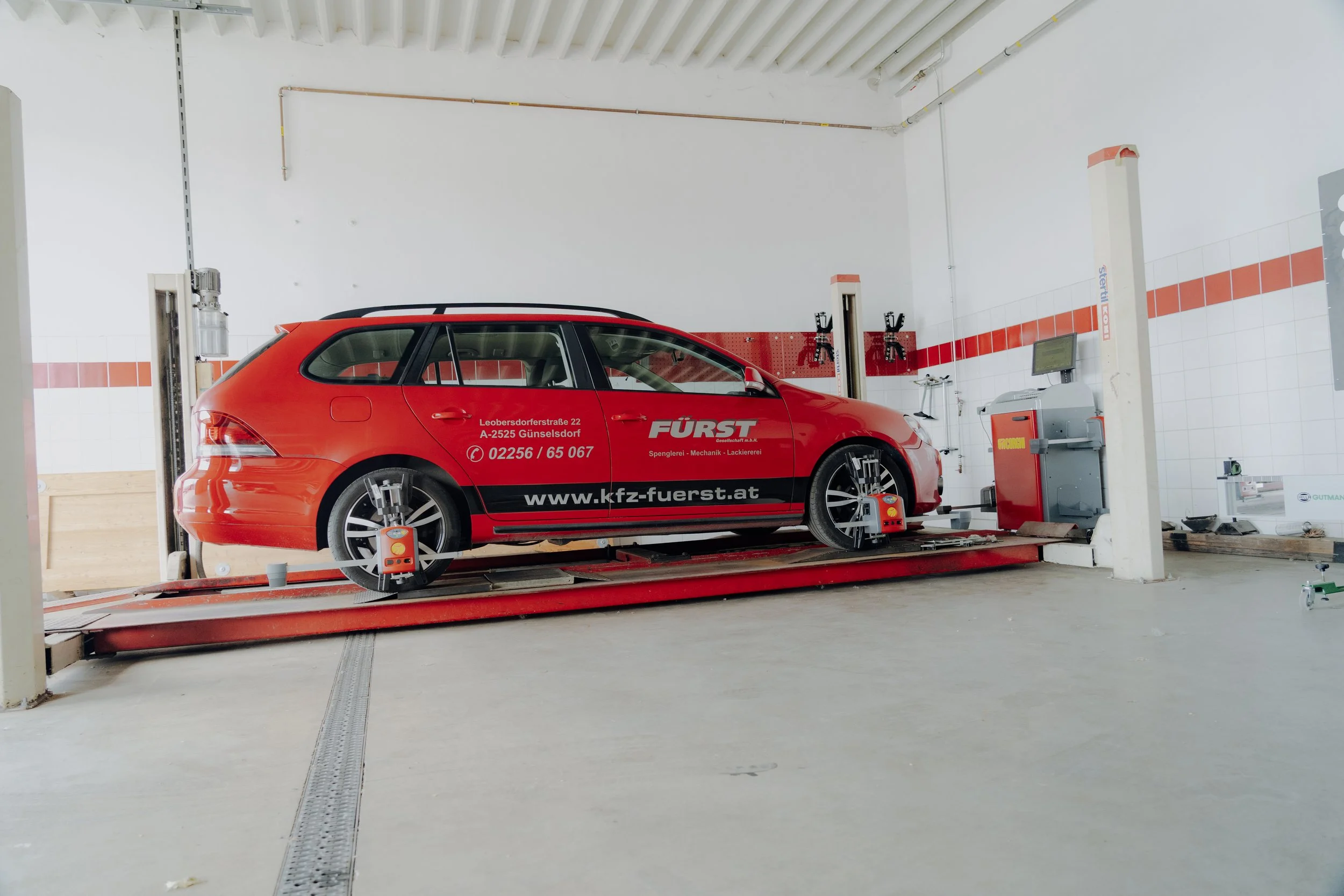 Roter PKW wird in einer auto Werkstatt auf einer Prüfmaschine getestet.