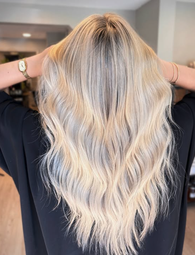 Back view of a woman with long, wavy, blonde hair.