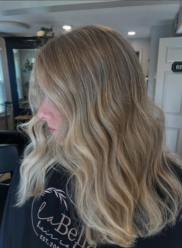 Side view of a woman with wavy blonde hair in a salon.
