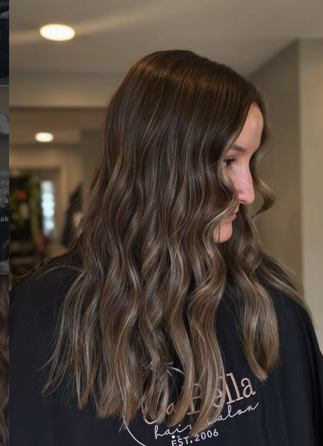 Side profile of a woman with long, wavy brunette hair, in a salon setting.
