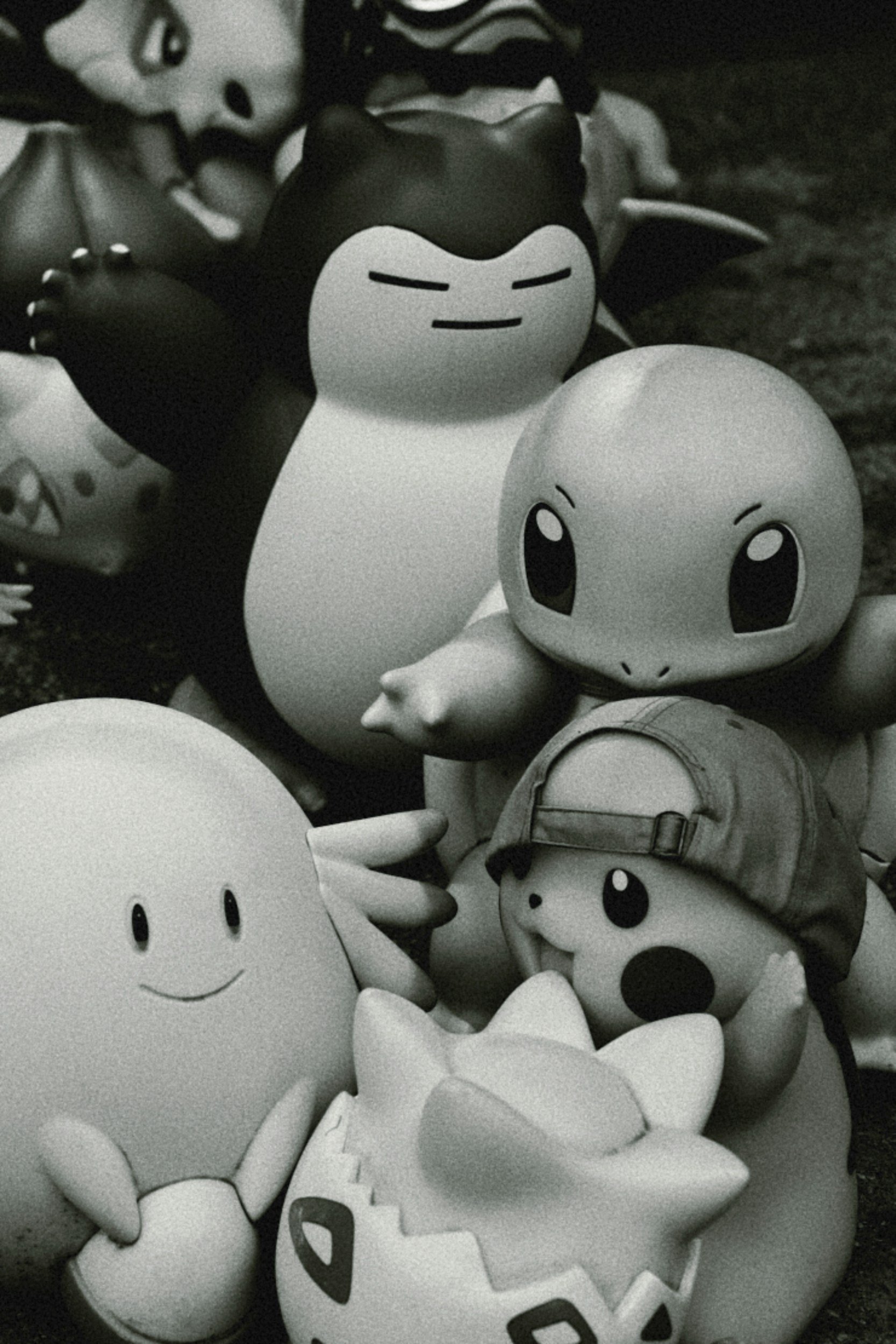 Collection of various Pokémon toys, including Pikachu, Squirtle, and other characters, in black and white.