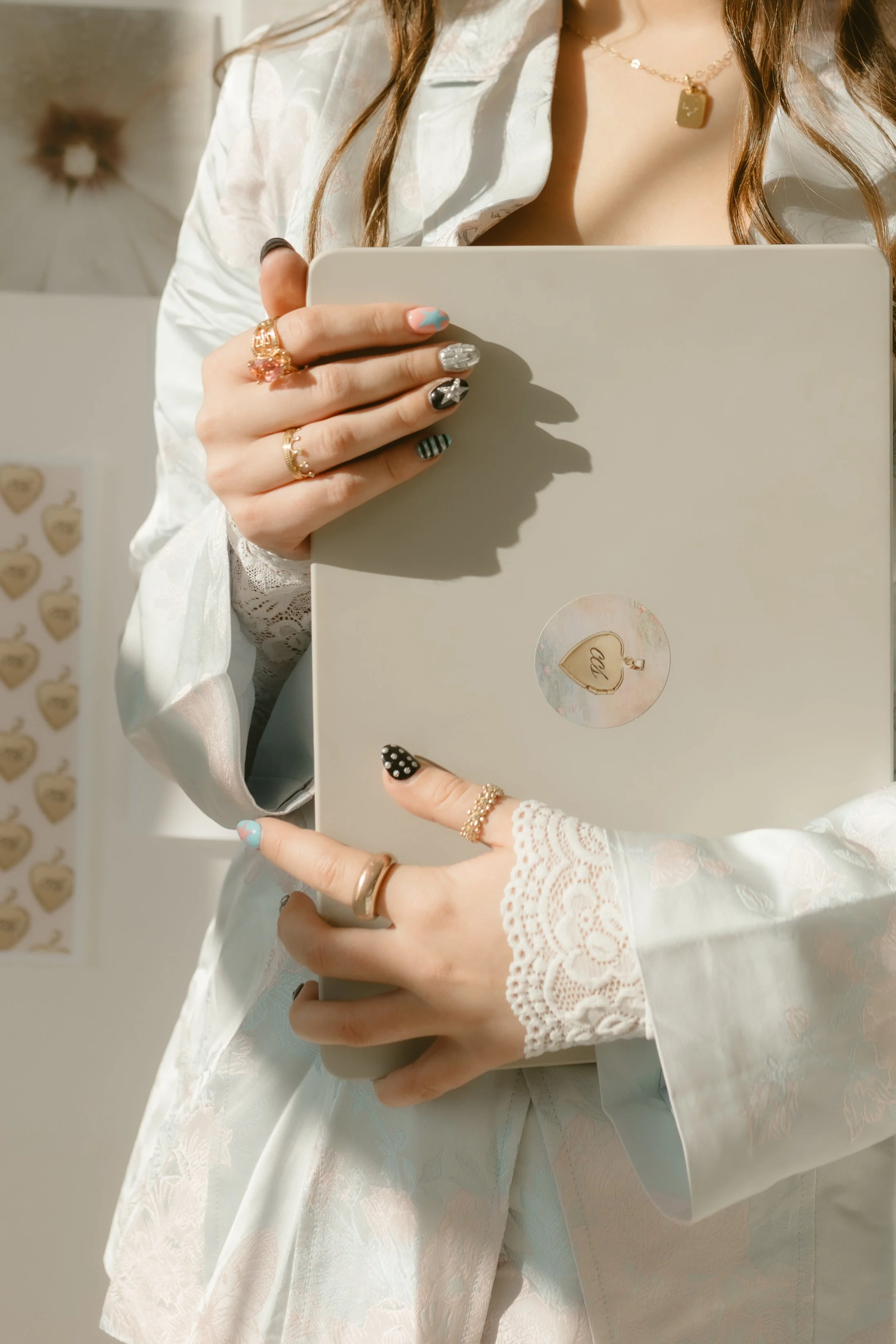 A woman wearing white lace and satin clothing holds a beige gift box with a circular sticker that has a heart and the word "Call" on it.
