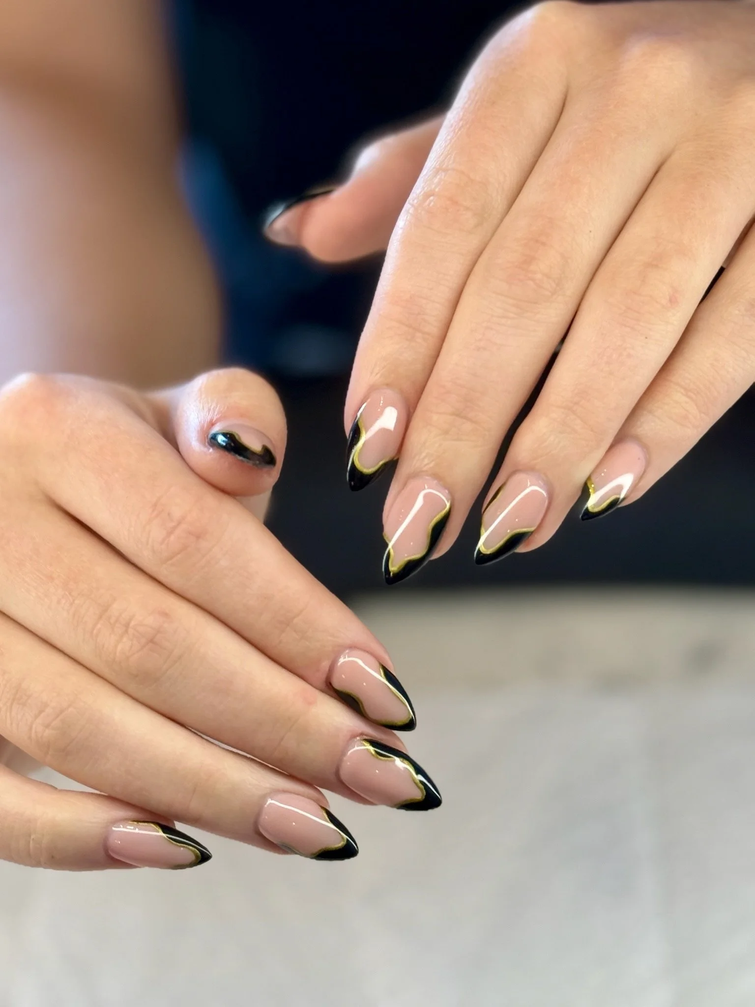 Close-up of hands with manicured nails featuring a black, white, and yellow zigzag design.