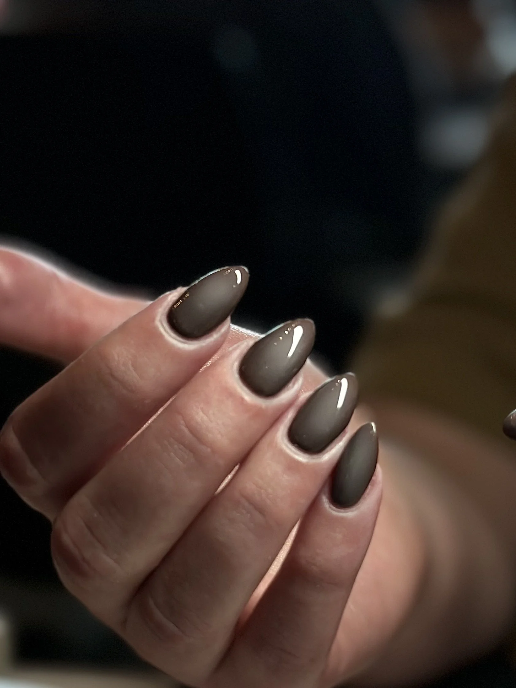 Close-up of a hand with manicured nails painted in a taupe color with a white tip, touching an older person's hand.