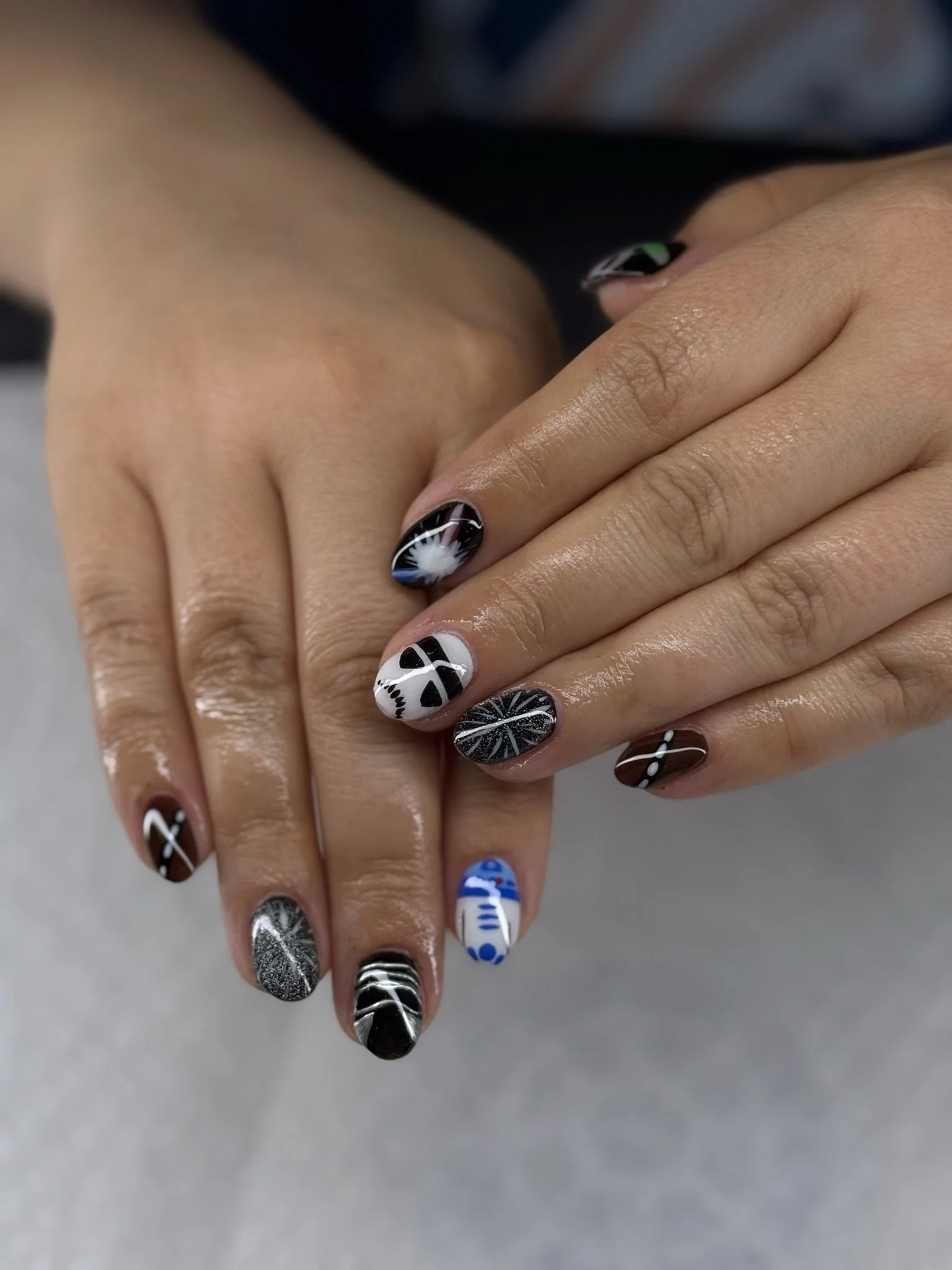 Close-up of hands with black, white, and blue patterned nail art featuring various unique designs.