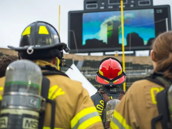 Firefighters practicing scuba diving, viewing underwater imagery on a large screen.