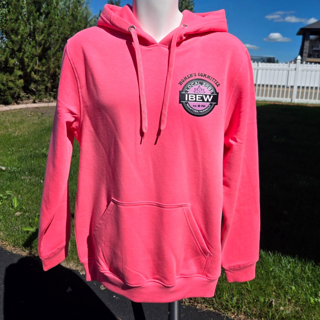 Pink hoodie with a logo on the front that reads 'Women’s G Cammittee, Local 2085, IBEW' and features a black and white design with a purple maple leaf, worn on a mannequin outdoors.