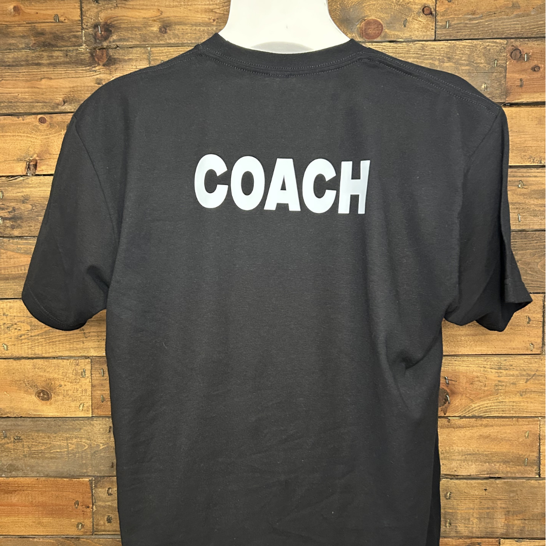 Black T-shirt with the word "COACH" printed in white on the back, hanging against a wooden background.