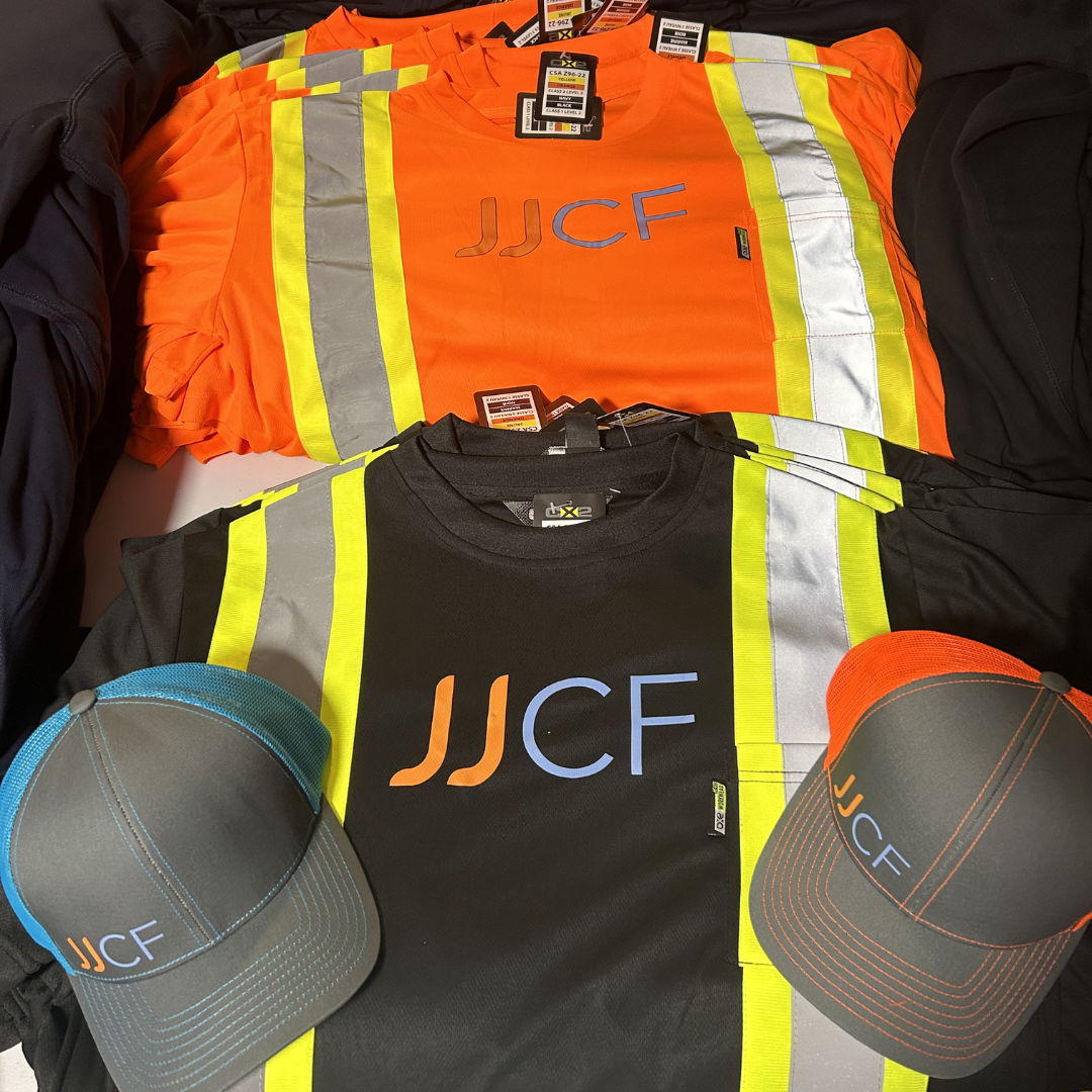 High-visibility safety shirts with reflective stripes, branded with JJF logo, along with two JJF-branded baseball caps, one gray with blue accents and one black with orange accents.