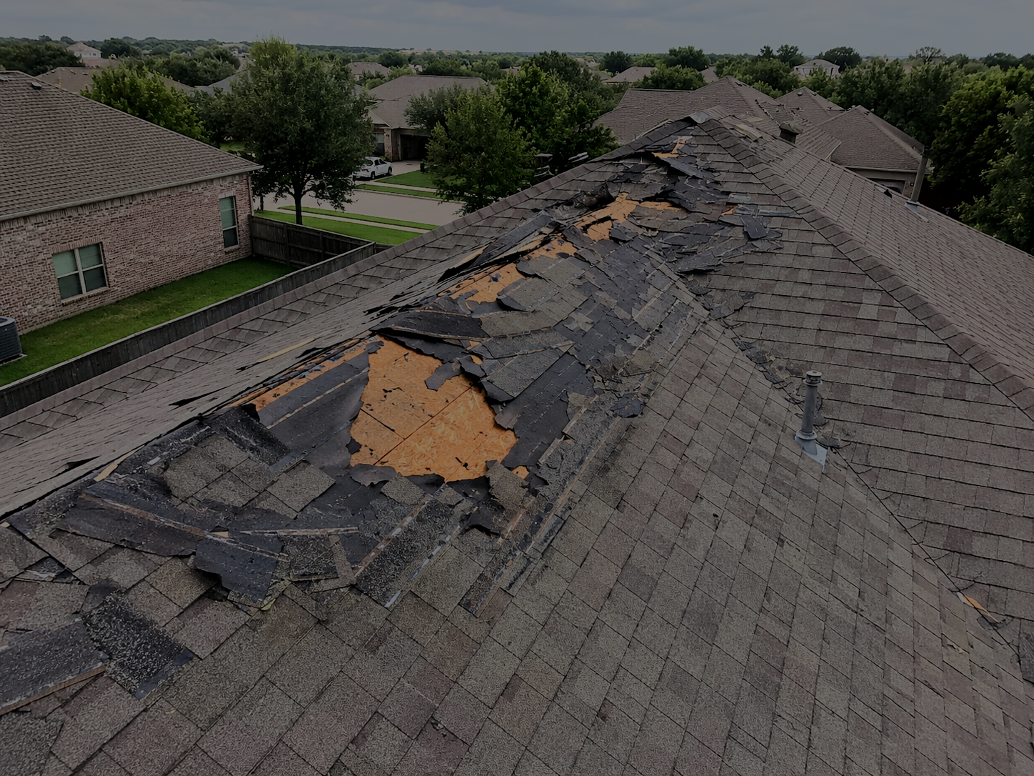 Exterior storm damage to asphalt shingles on a Houston residential roof