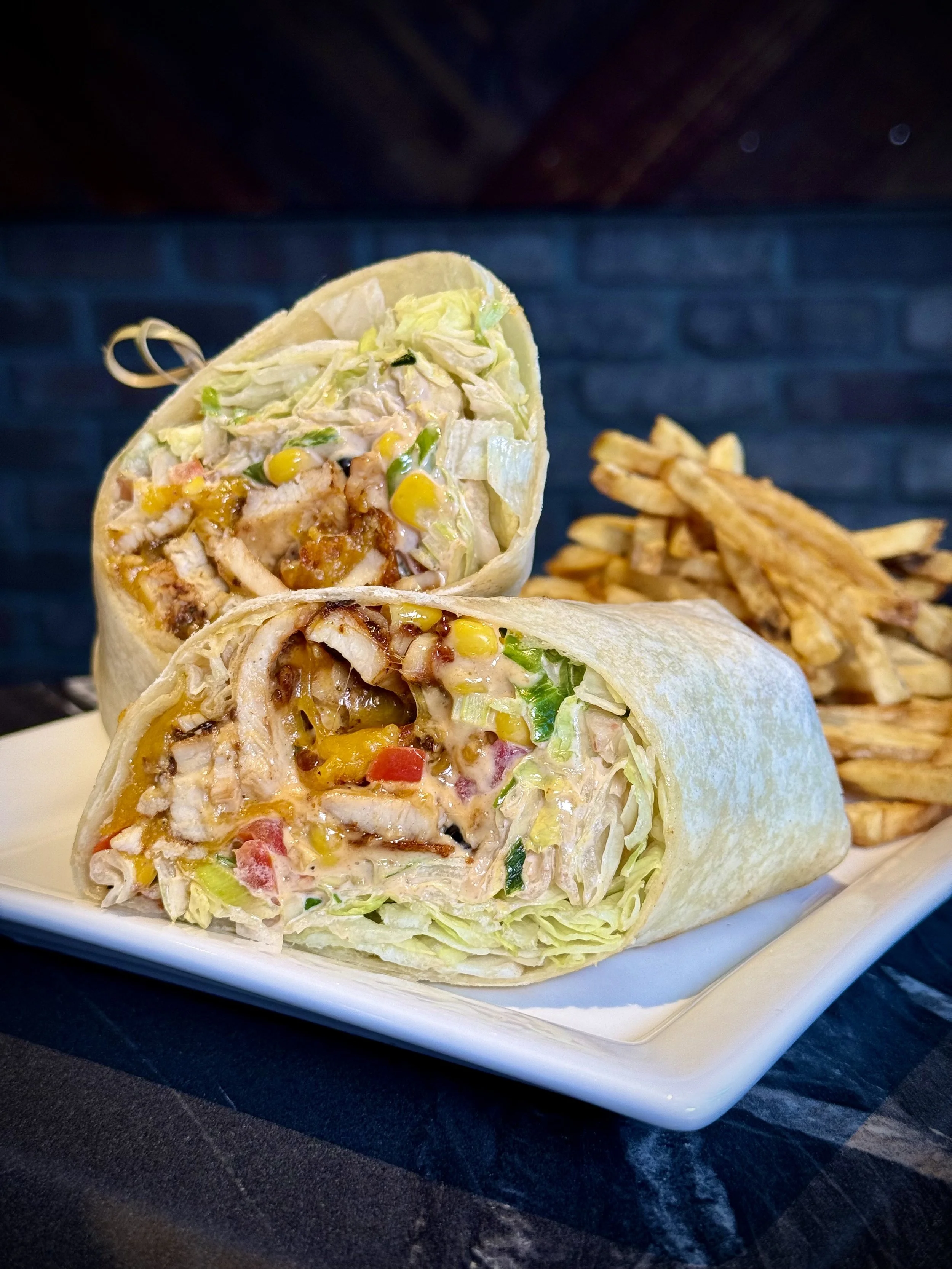 Chipotle Chicken Wrap
Marinated chipotle chicken, chopped up and tossed with cheddar cheese, fresh tomatoes, black beans, corn, white & green onions, shredded lettuce and chipotle aioli, wrapped and grilled in a flour