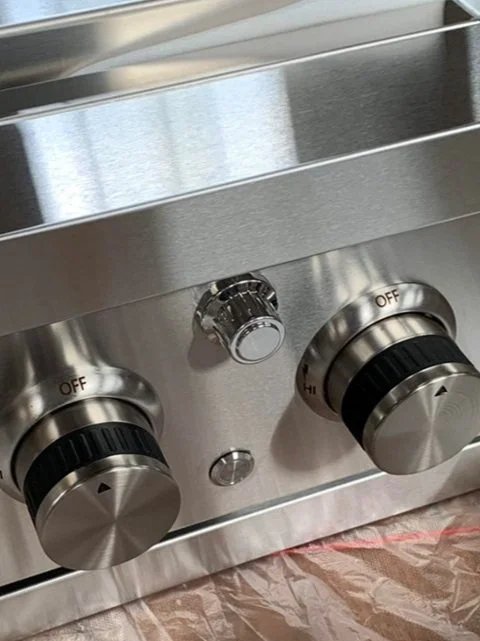 Close-up of stainless steel control knobs on a kitchen stove or oven.