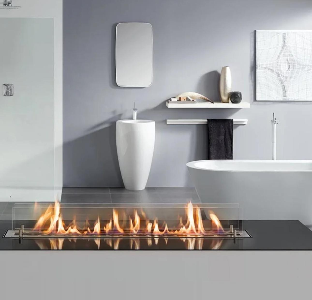 Modern bathroom with a gas fireplace, white freestanding bathtub, gray walls, and minimalist decor.