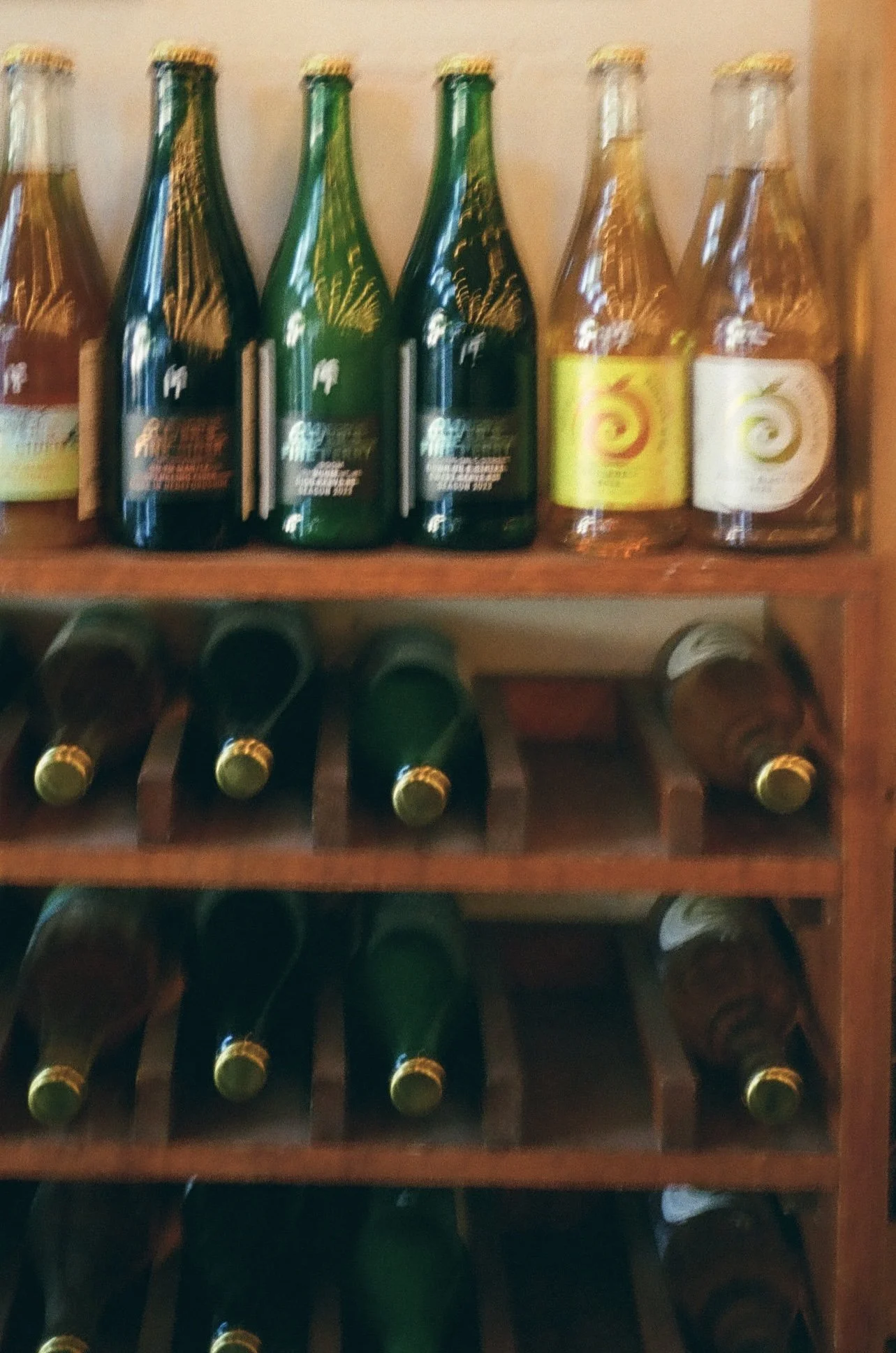 A wooden wine rack filled with multiple bottles of wine, with some bottles placed horizontally on the lower shelves.