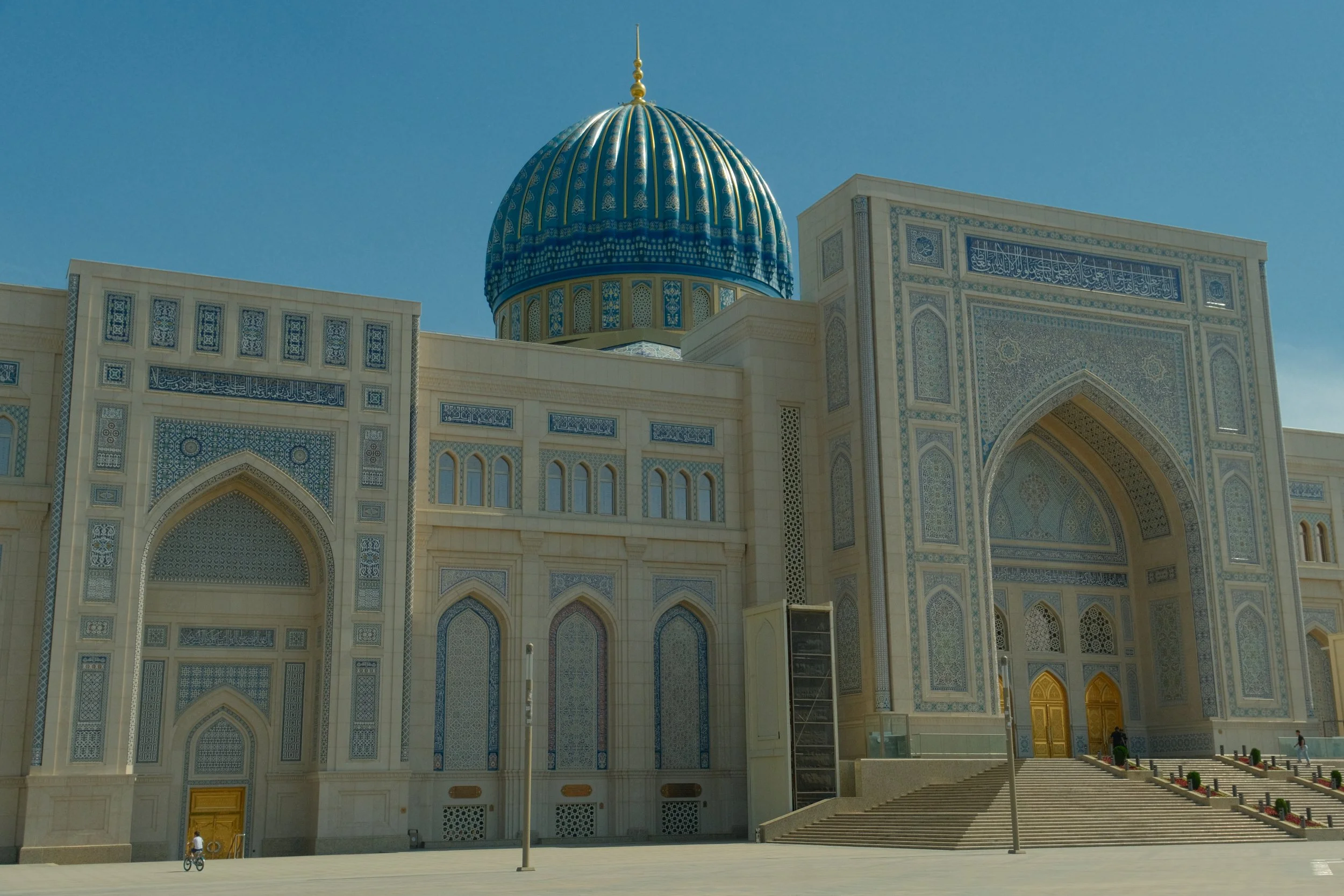 Hazrati Imam mosque facade with turquoise dome, ornate blue tilework, and golden entrance doors in bright daylight, Tashkent, Uzbekistan
