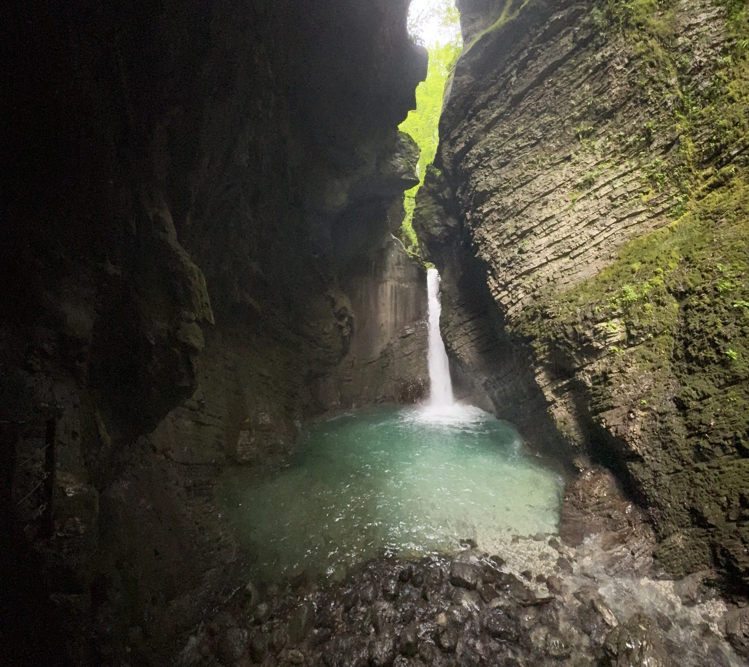 Slap Kozjak waterfall pouring through a narrow limestone gorge into a turquoise pool near Kobarid, Slovenia