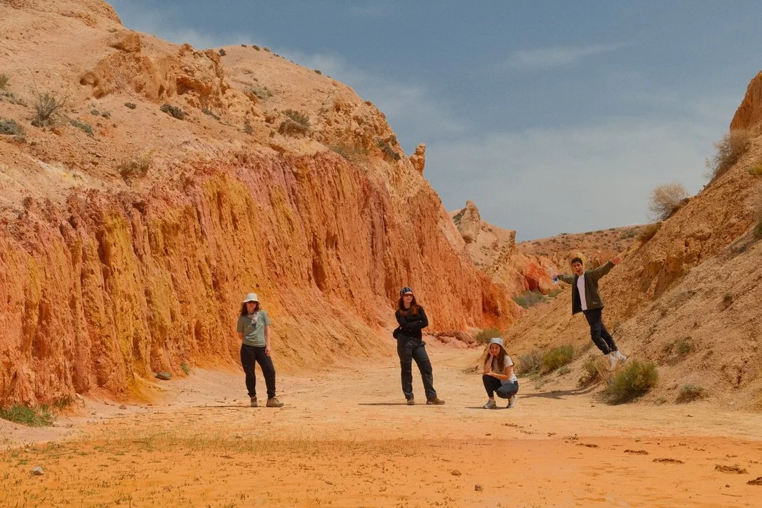 Hikers among the red sandstone formations of Fairy Tale Canyon on Issyk-Kul's southern shore