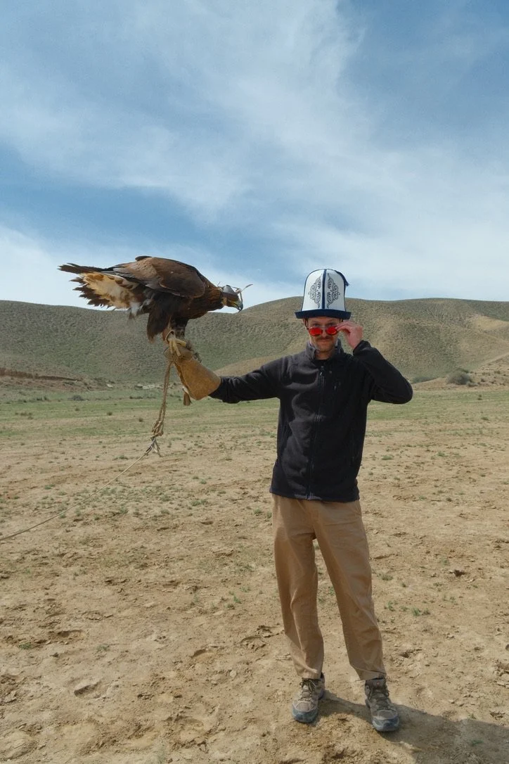 A traveler holding a golden eagle on a gloved arm after an eagle hunting demonstration in Kyrgyzstan