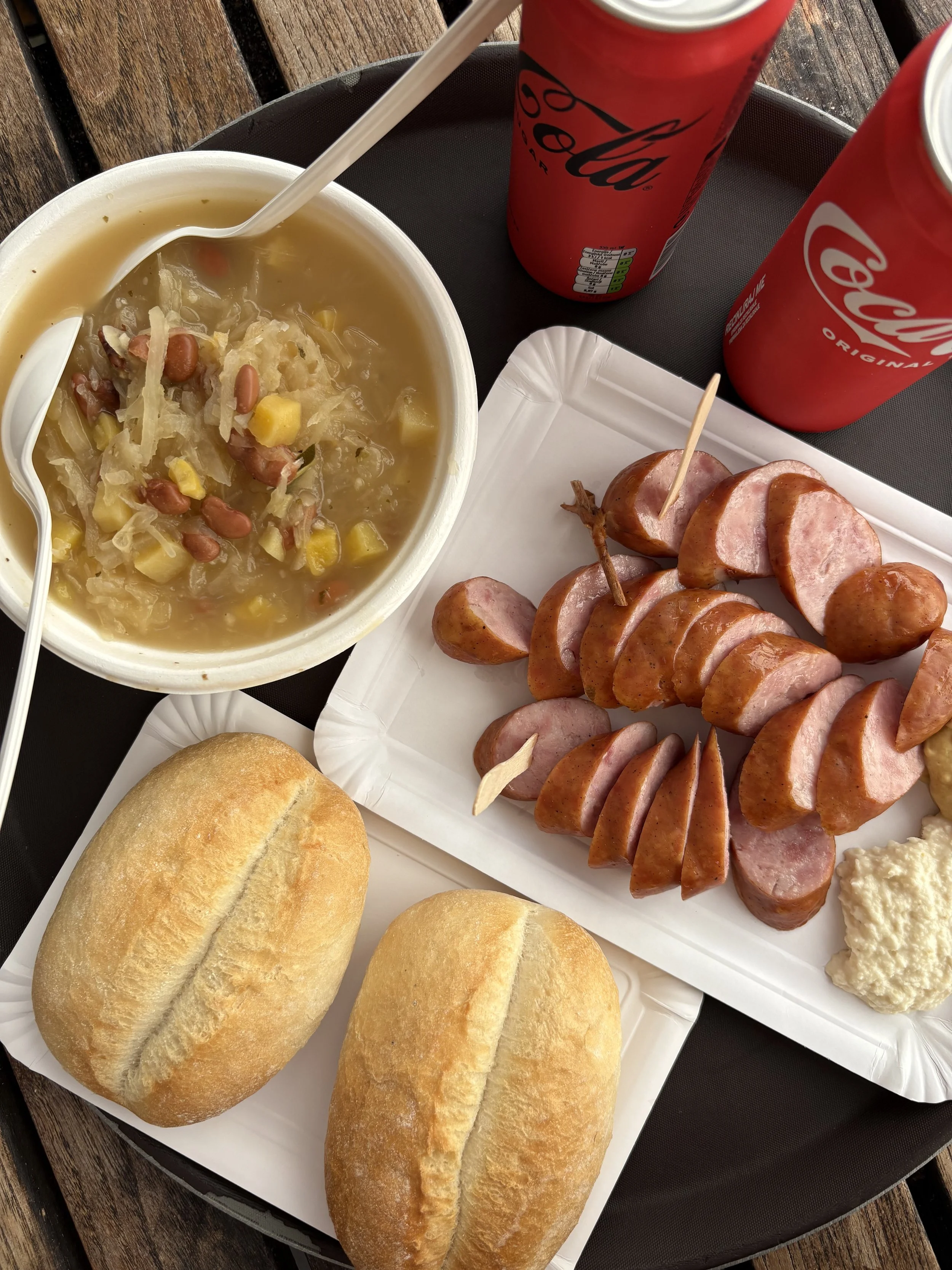 Bowl of traditional Slovenian jota stew with sauerkraut and beans, served with sliced sausage and bread rolls