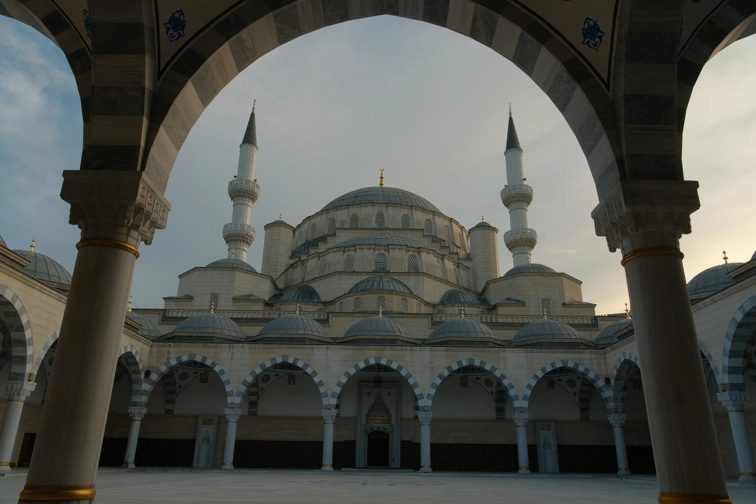 Domes and twin minarets of Bishkek's Central Mosque framed by a stone archway