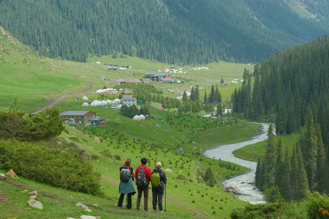 Hikers looking down at yurt camps in the Altyn-Arashan valley near Karakol, Kyrgyzstan