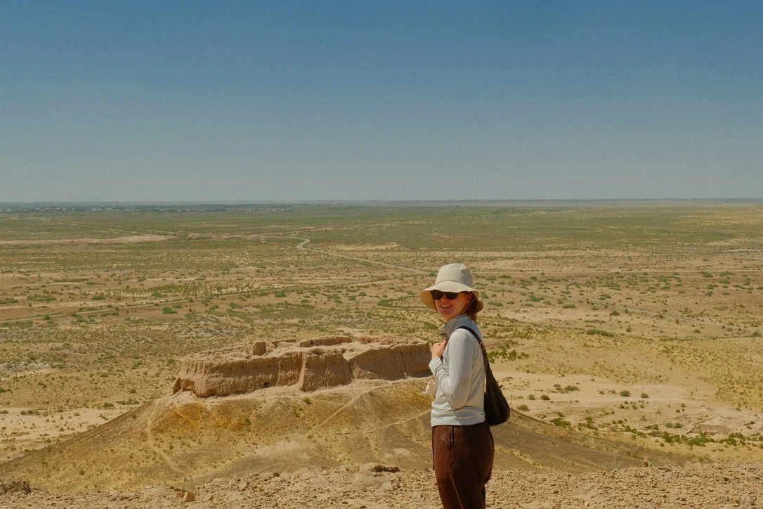 Traveler standing atop ancient Khorezm fortress ruins overlooking the vast Karakalpakstan desert steppe, Uzbekistan