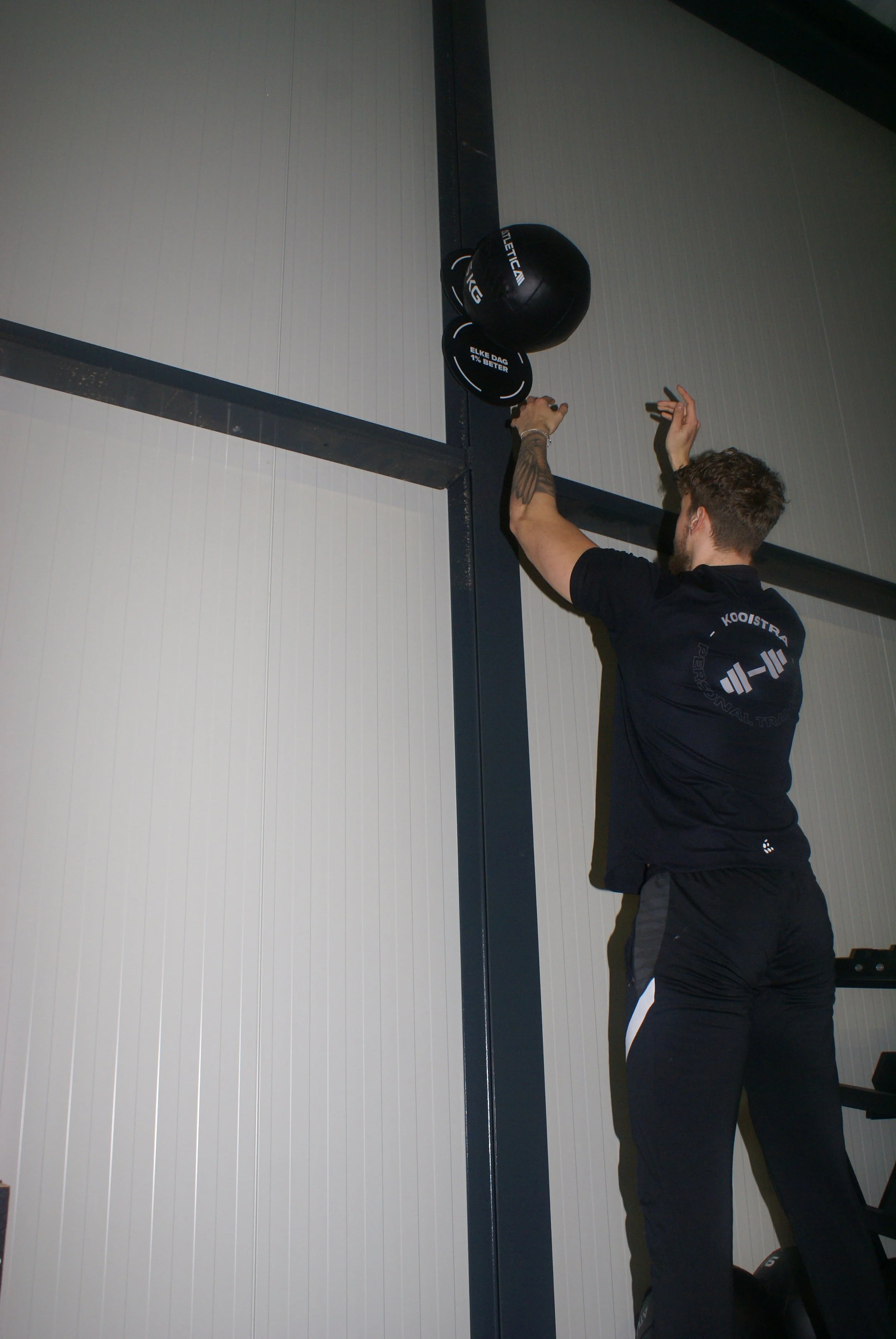 Een man doet een fitness oefening met een medicineball in een sportschool.