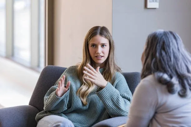 A young woman having a conversation with an older woman in a therapy or counseling session.