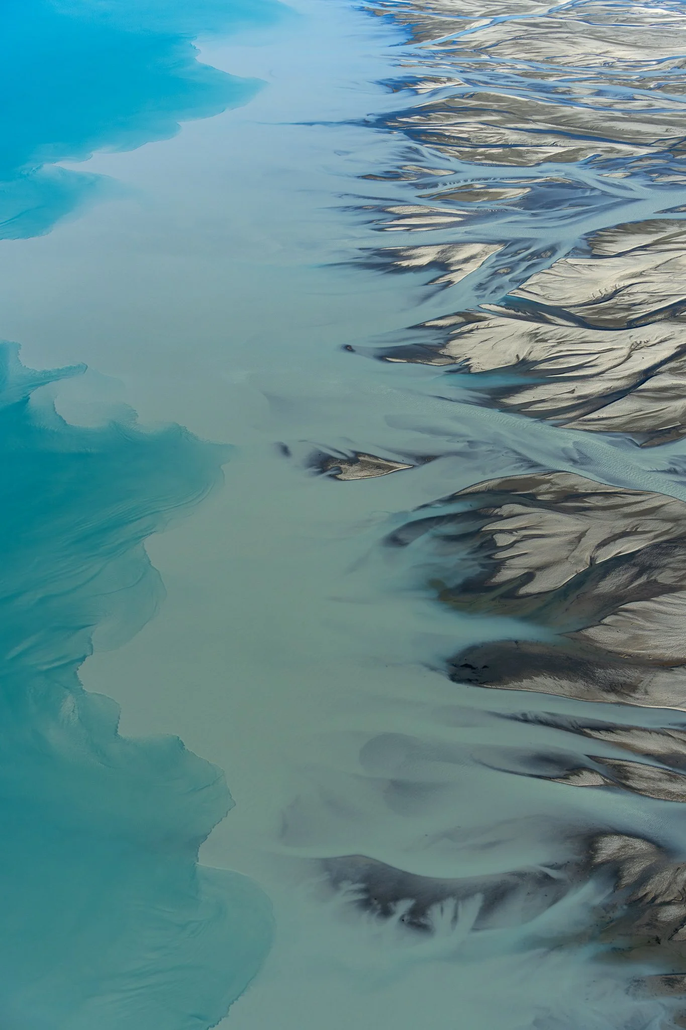 Aerial view of a glacier melting into a lake, with ice formations on the water's surface.