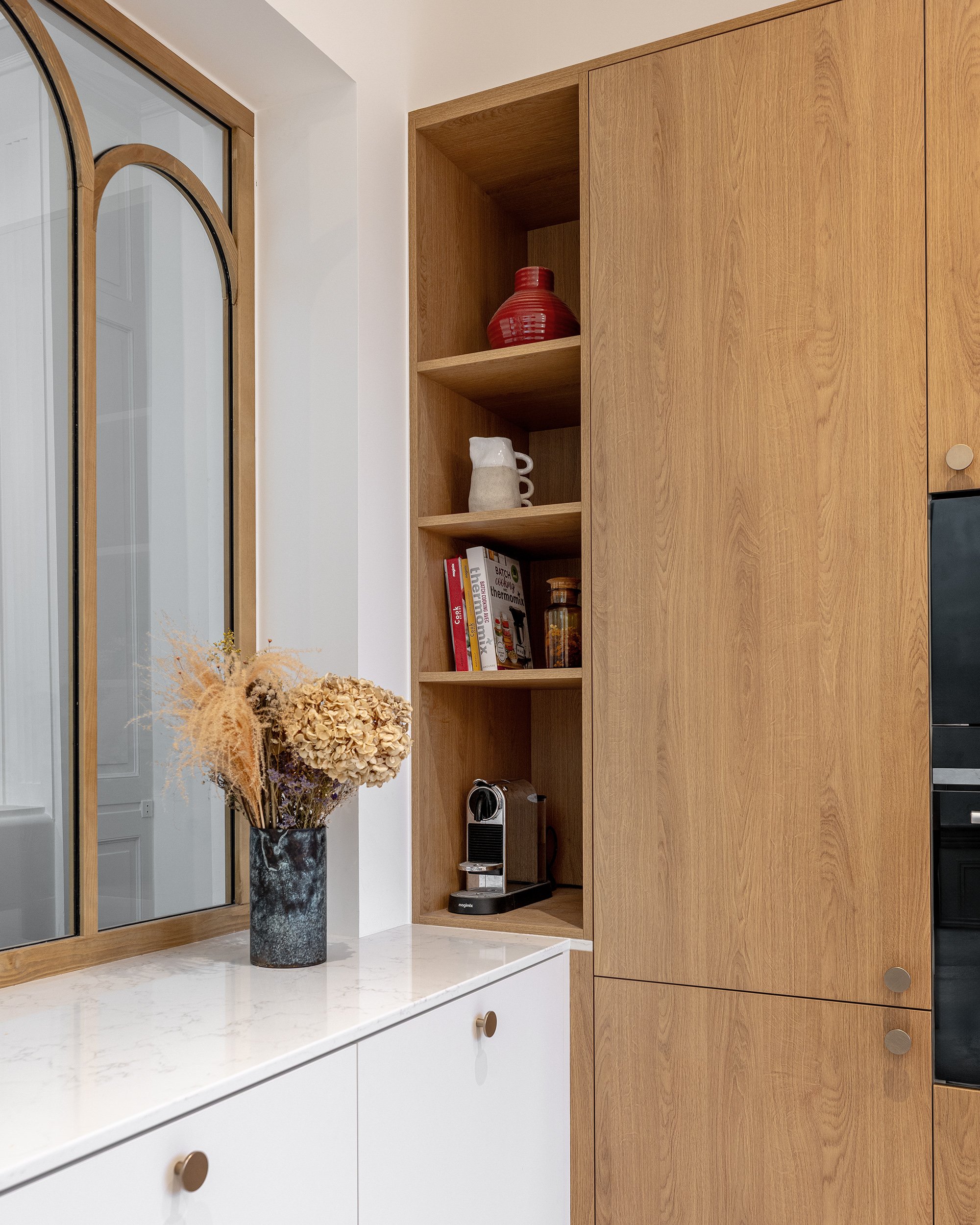 Vue de la cuisine ouverte avec espace repas, mobilier sur mesure et carrelage graphique.