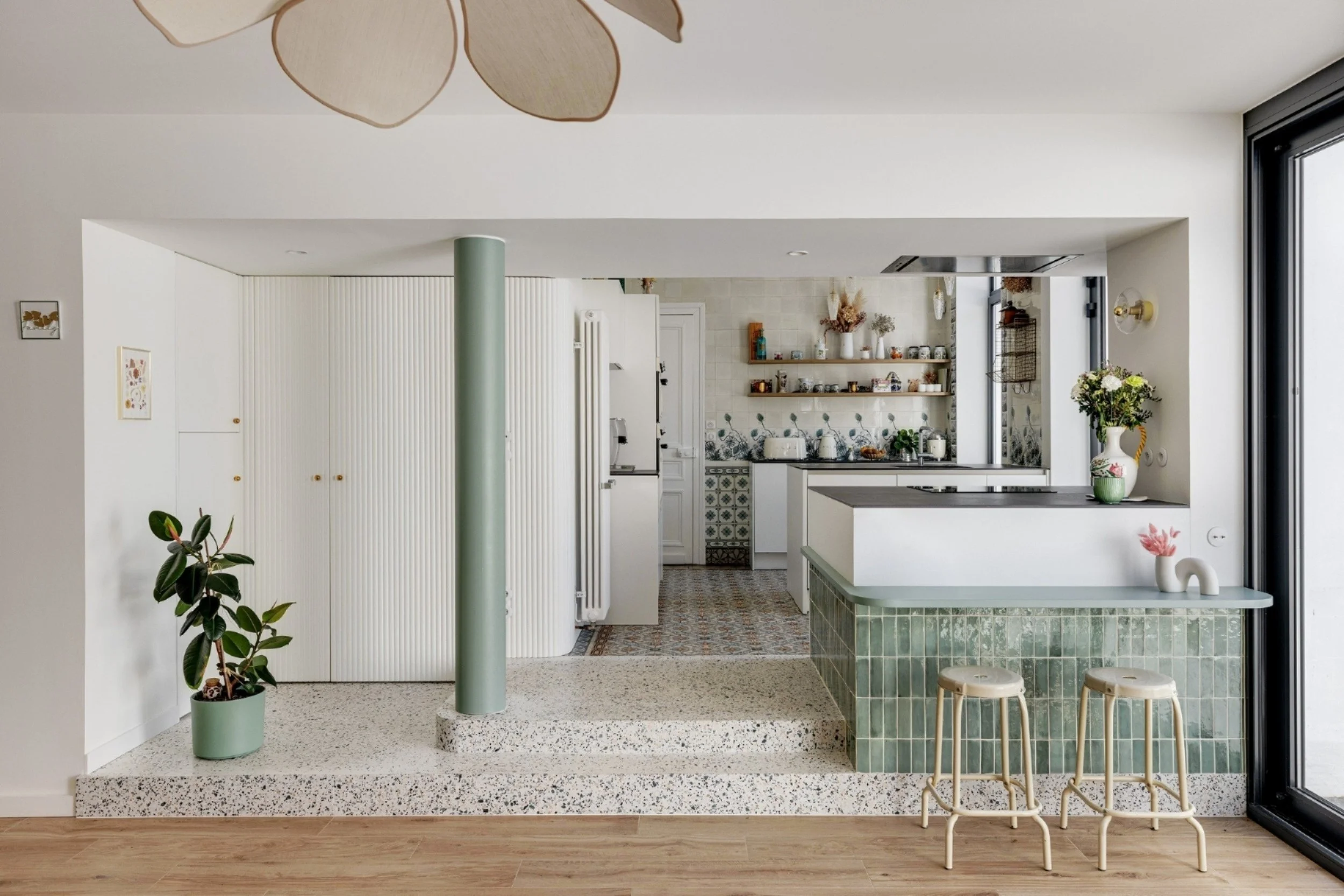 Cuisine ouverte avec îlot central en terrazzo et zelliges verts dans une maison rénovée à Provin.