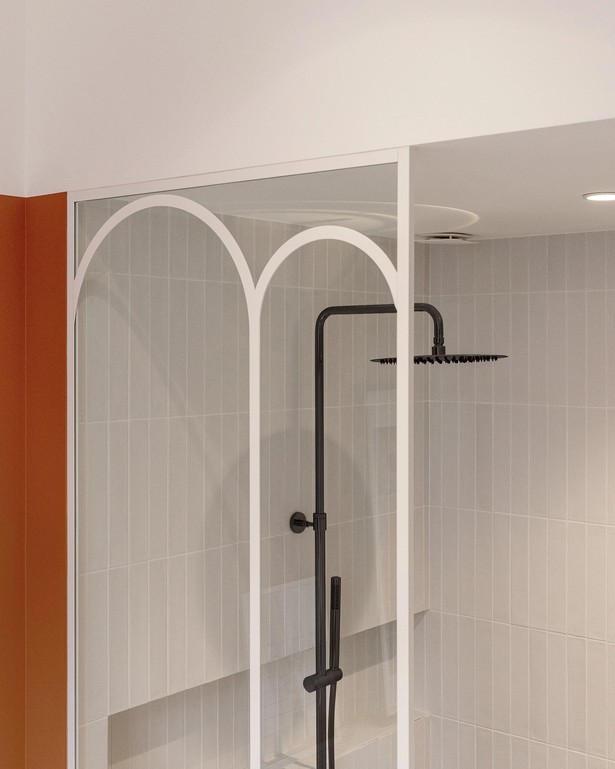 Douche à l'italienne avec verrière blanche, robinetterie noire et faïence verticale.