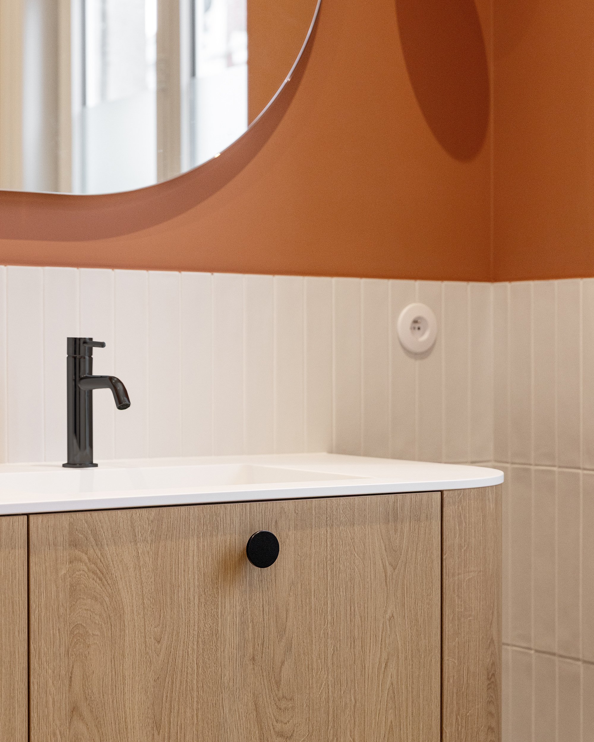 Détail du meuble vasque en chêne, du plan blanc et de la robinetterie noire.