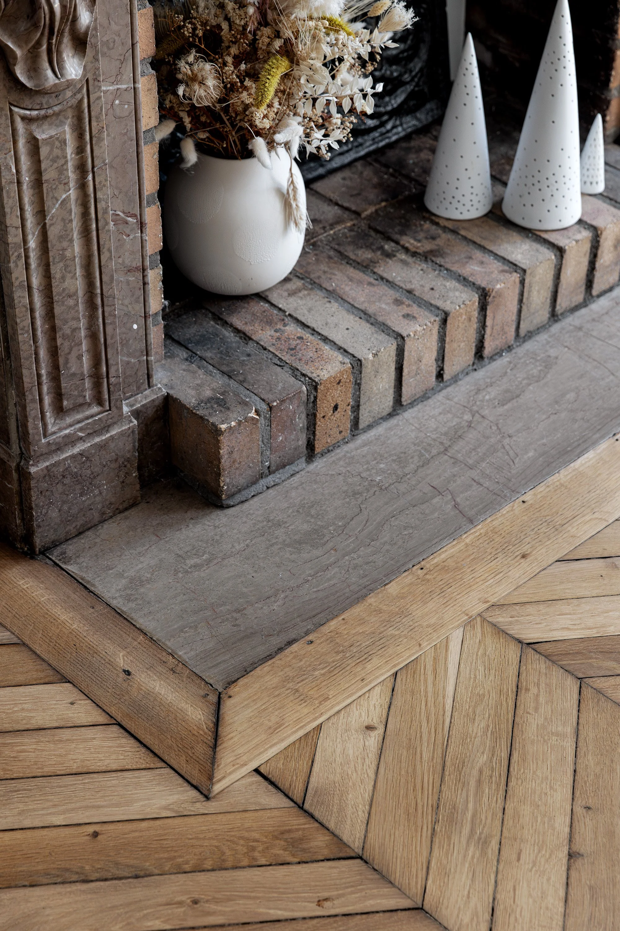 Détail du foyer de cheminée, du parquet en point de Hongrie et des finitions d'origine conservées.