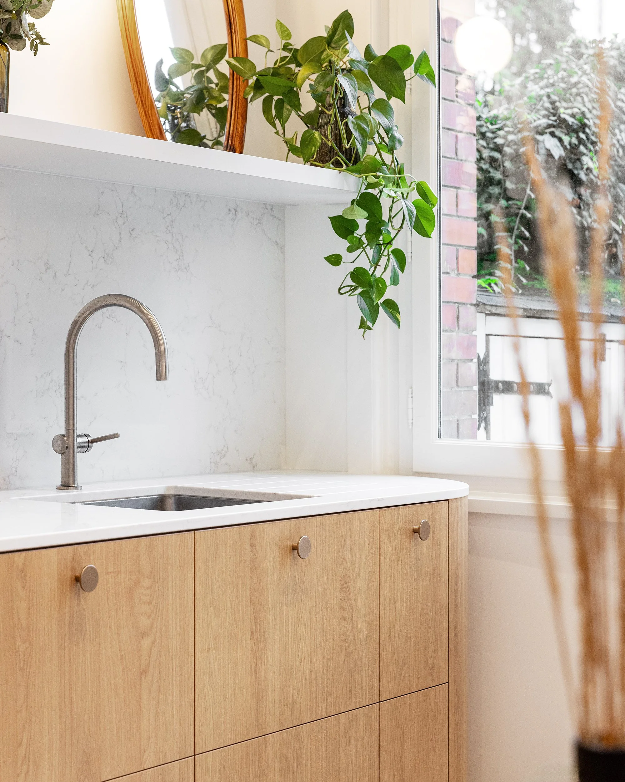 Détail des rangements sur mesure en chêne et du plan de travail en pierre dans une cuisine rénovée.