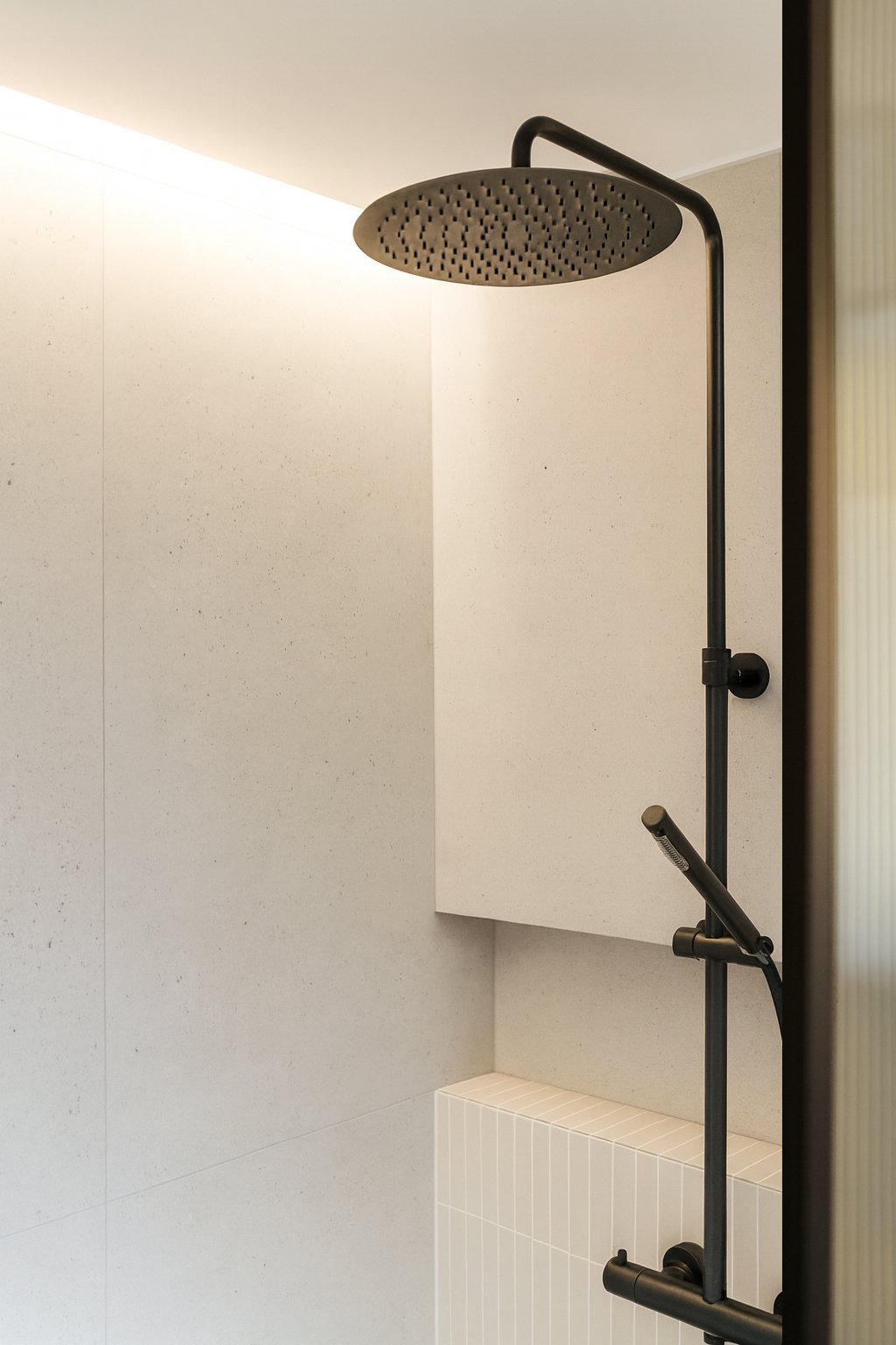 Douche à l'italienne avec robinetterie noire et éclairage indirect dans une salle de bain sur mesure.