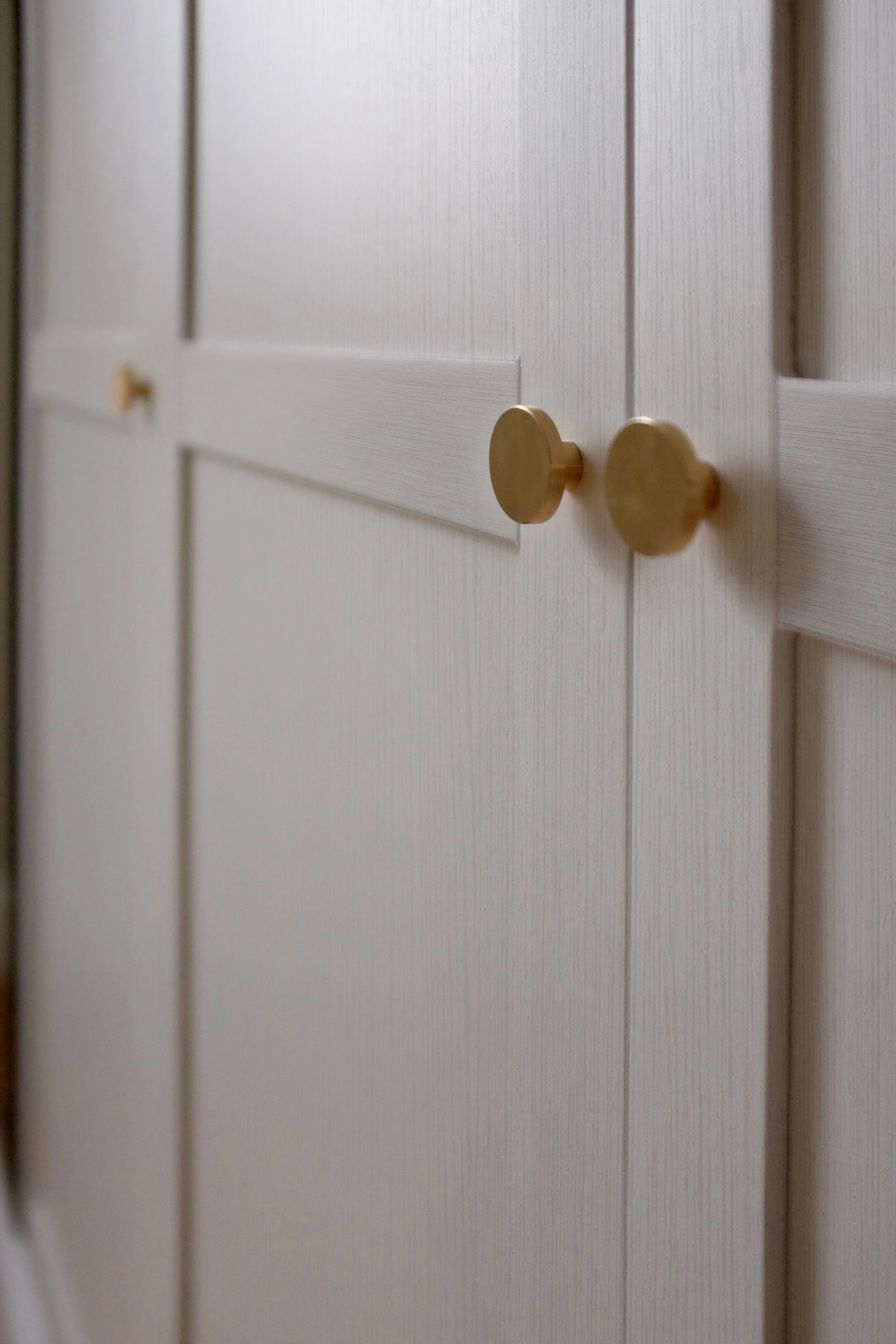 Détail des façades de rangement sur mesure avec poignées en laiton.