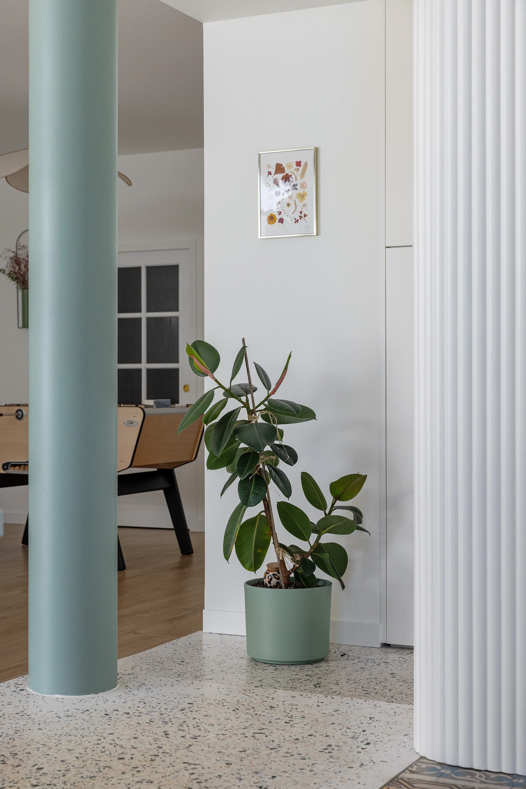 Colonne vert sauge et rangements sur mesure intégrés dans une cuisine contemporaine.