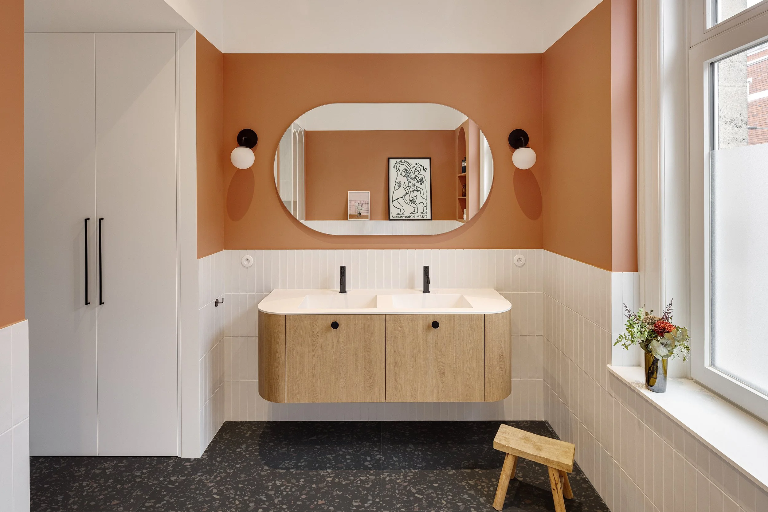 Salle de bain avec double vasque suspendue en chêne, miroir sur mesure et murs terracotta.
