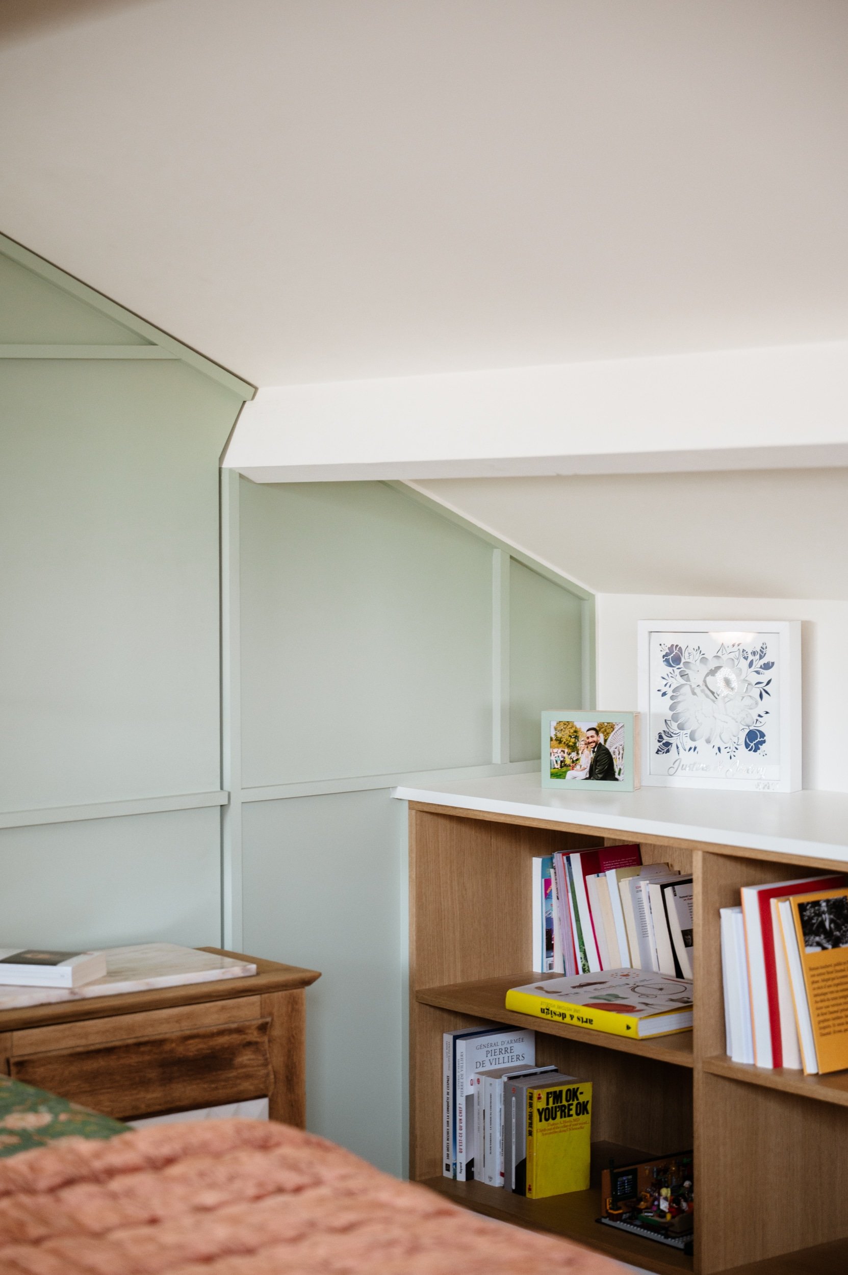 Bibliothèque en chêne intégrée dans une chambre rénovée sous toiture.
