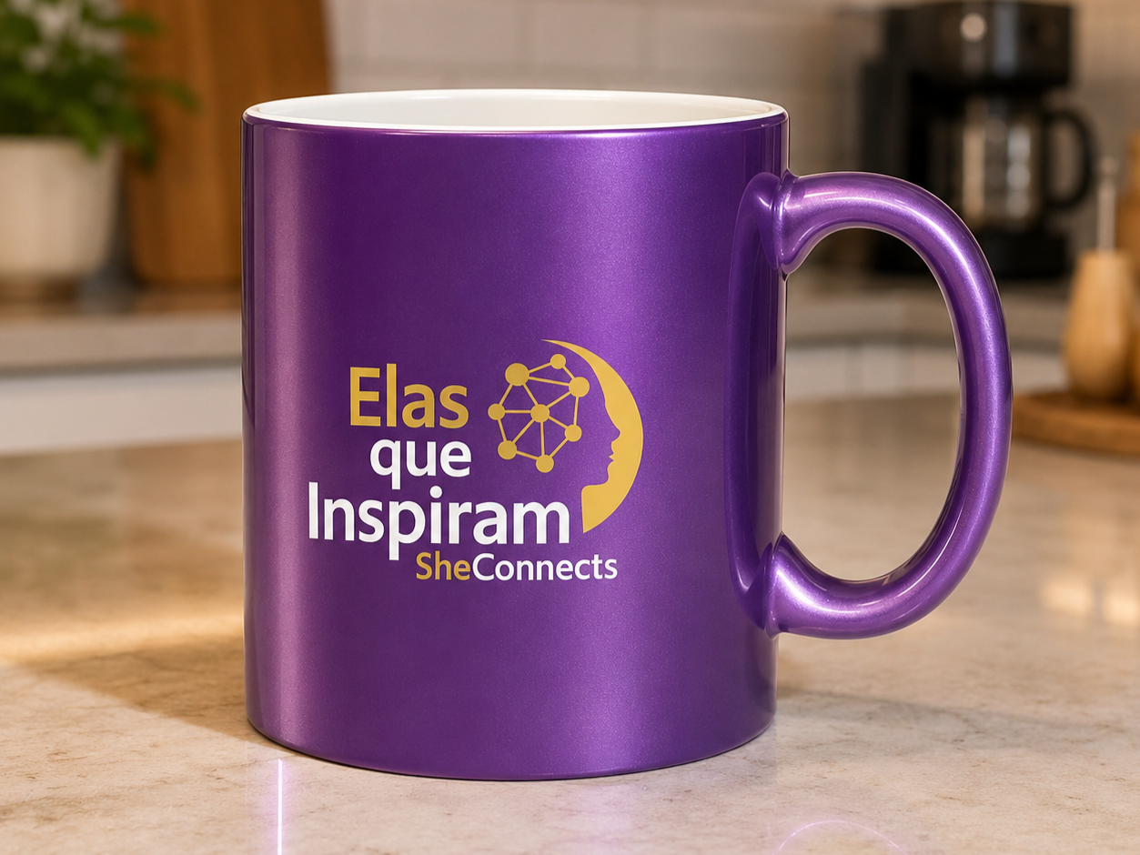 Caneca roxa com logo e texto em português e inglês, sendo 'Elas que Inspiram She Connects', sobre uma mesa de cozinha.