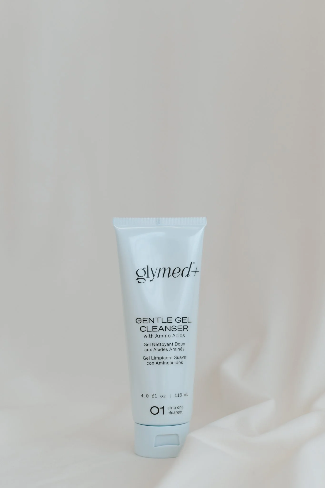 A white tube of Glymed Gentle Gel Cleanser with black text, standing upright on a white surface against a neutral background.