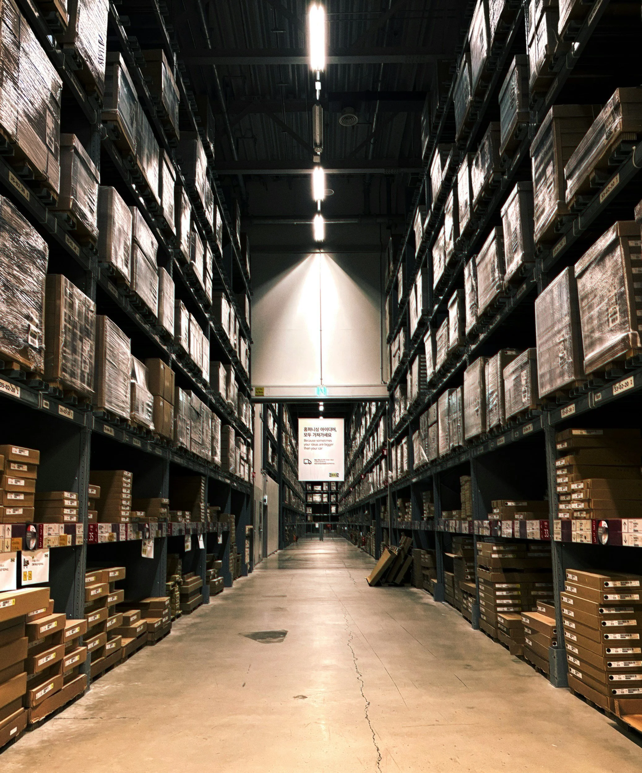 Large commercial warehouse aisle with tall shelves full of cannabis or hemp inventory.