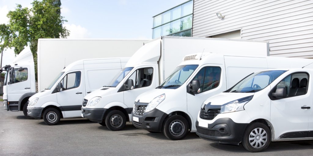 Fleet of white cannabis delivery and distribution vans parked outside a commercial facility