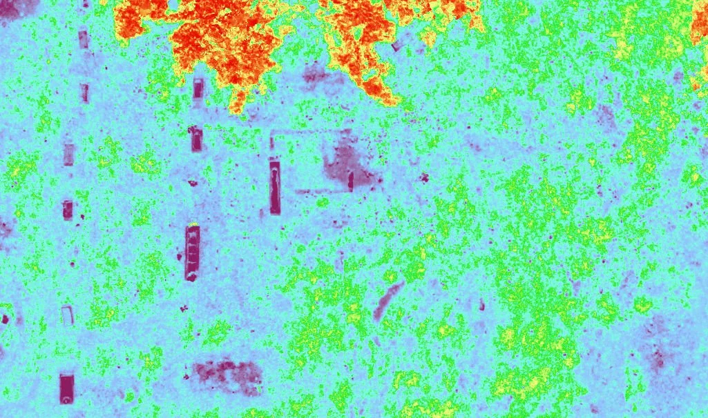 Color-enhanced aerial view of a landscape with scattered buildings, roads, and trees.