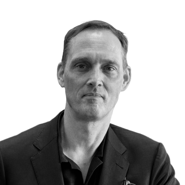 Black and white portrait of a man wearing a suit and dress shirt, looking directly at the camera with a serious expression.
