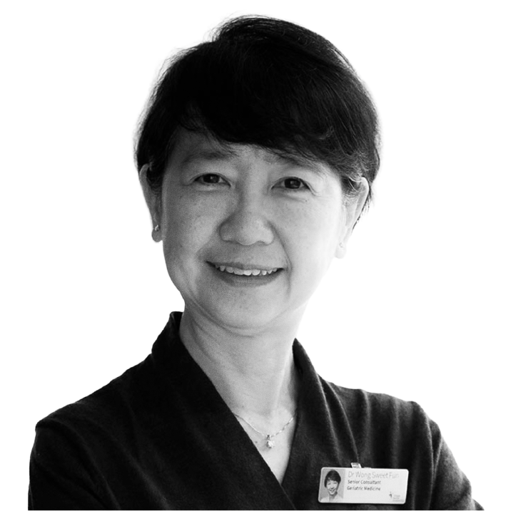 Black and white portrait of a woman with short hair, smiling, wearing a dark top and a name tag.
