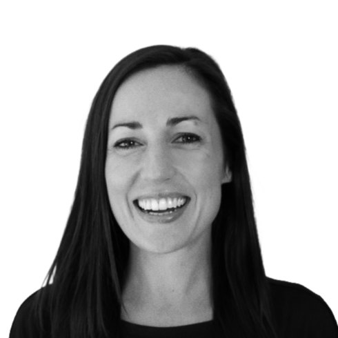 Black and white photo of a smiling woman with long dark hair, wearing a dark top.